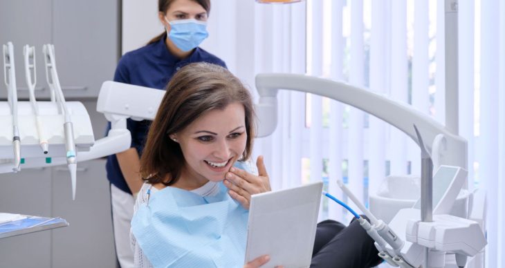 woman admiring her beautiful smile at the dentist